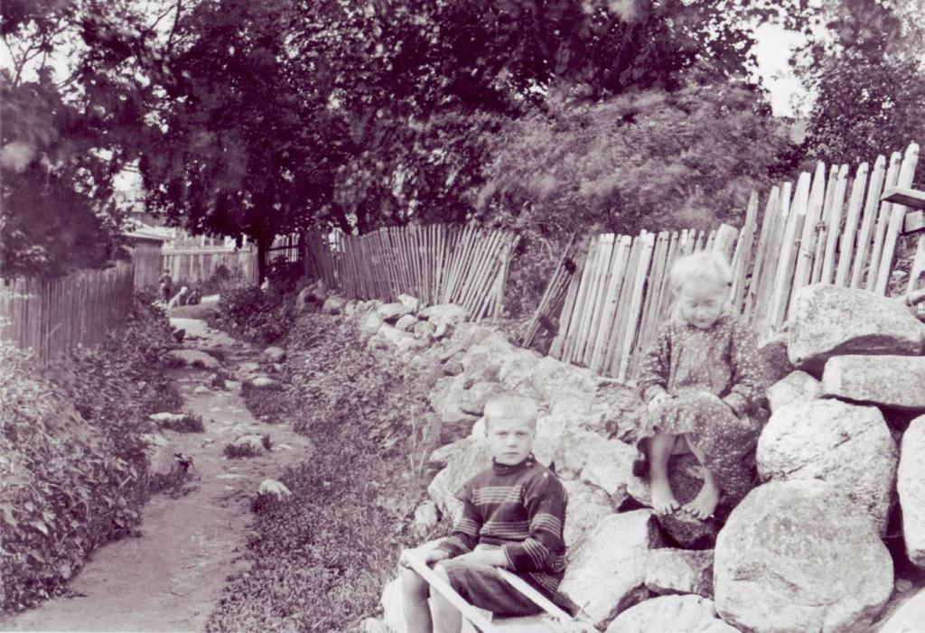 pääsisäänäynnille. Tytön taana vasemmalla on hedelmäpuita. Sadevesi erättiin atolta tynnyriin. (Porvoon museo) Lähes oonaan ivettyjä pihoja oli useita Joiadun varrella ja iron torilla.