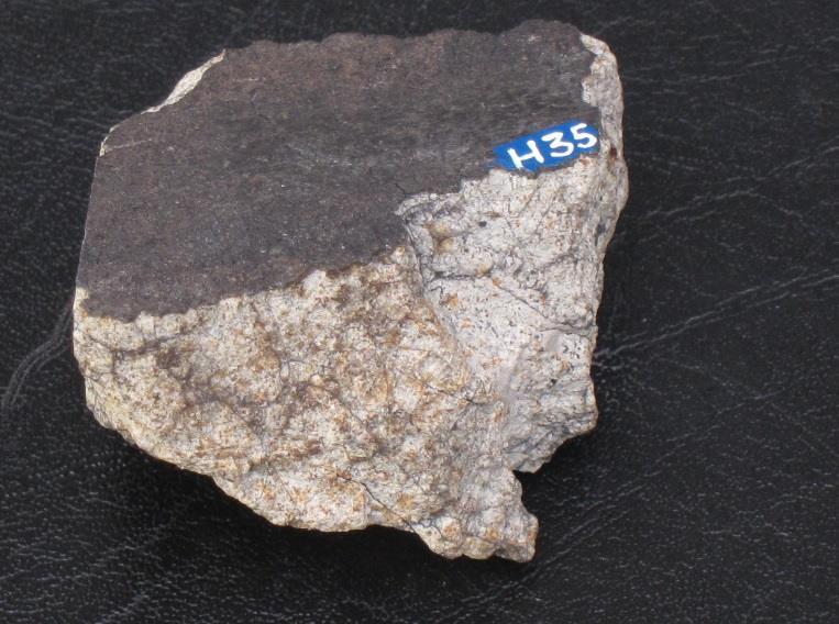 Huomaa yläosan musta sulamiskuori ja vaalean kiviaineksen breksioitunut