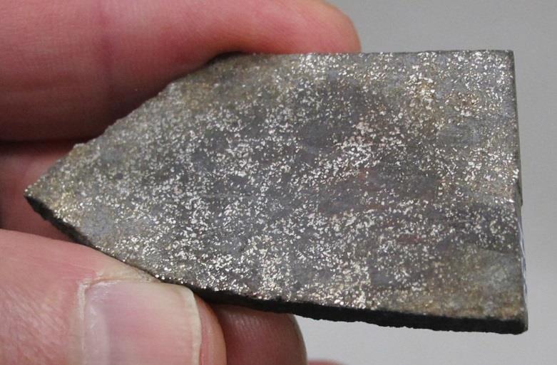 Kappale Valkealan meteoriittia. Huomaa kuoren punaruskea, ruosteinen yleissävy ja sisäosan kiiltävät metallirakeet. Näyte H34. Kuva Eero Hanski. Kuva 36.