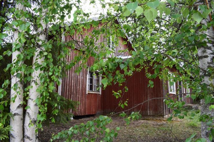 rakennuksen takaa aukeavan peltomaiseman reunalla.