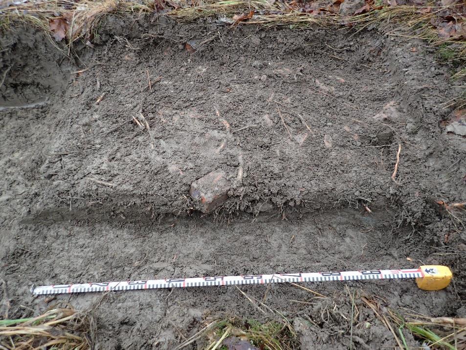 tiilen paloilla, pienillä kivillä ja saven sekaisella maalla (kaivannossa oli myös muutama pala kirkasta talolasia sekä posliiniastian paloja).