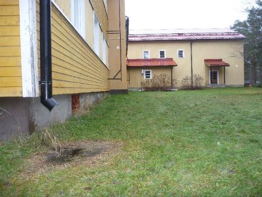 Paikoin rakennuksen takana maanpinta on tasainen. Kattosadevedet on ohjattu rännikouruilla sekä syöksyputkilla rakennuksen vierelle.