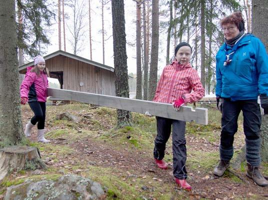 Lauri Potila valaa yhtä liiterin yhdeksästä anturasta. Sofia Holma ja Lilli Reko näyttävät, miten hirsi liikkuu kohti työmaata. Ohjaamassa Anita Niemenmaa. tamiseen.