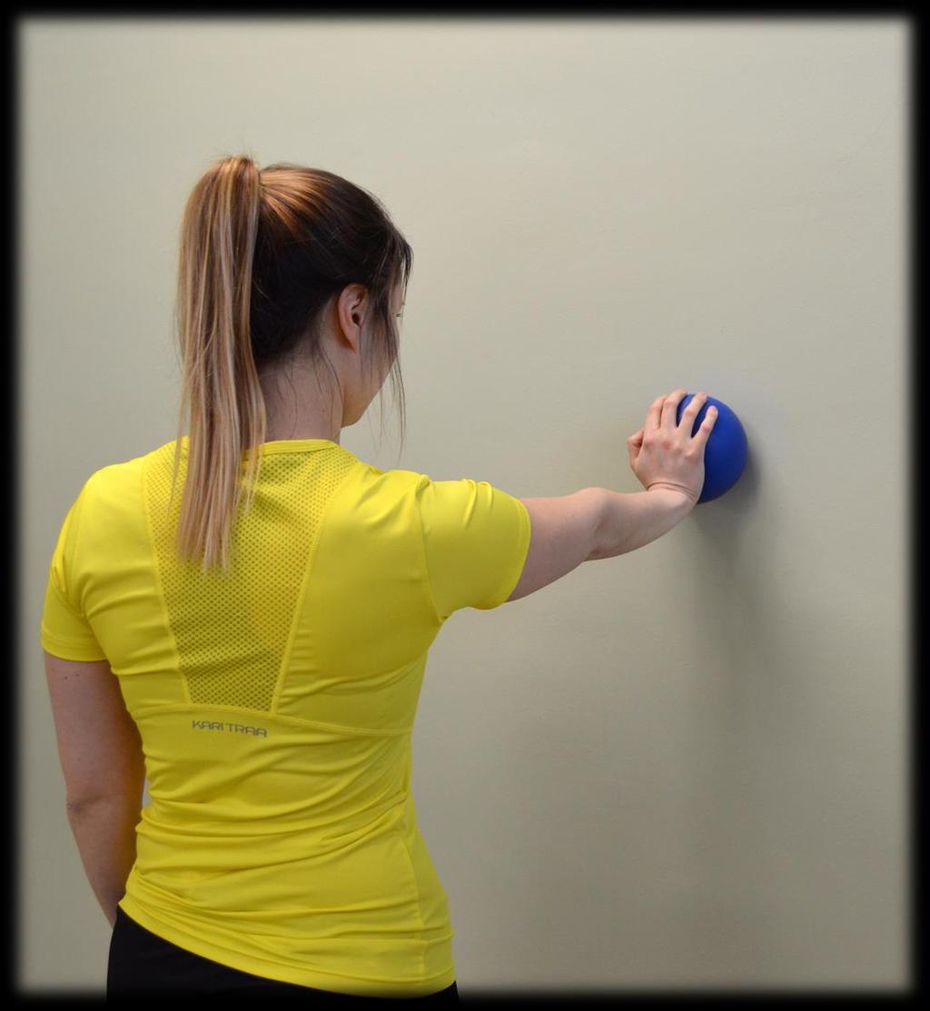 Lavan hallinnan harjoite 5: Pallon työntö seinää vasten Seiso tukevasti kasvot seinään päin ja aseta pallo seinän ja kuntoutettavan yläraajasi väliin kuvan osoittamalla tavalla.