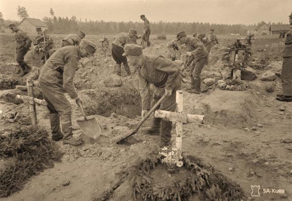 Kuvassa haudataan suomalaisia sotilaita. Edessä ovat vänrikki Sulo Elorannan (k.27.7.1941) ja sotamies Pentti Paanasen (k.28.7.1941 Ristisalmella) haudat Tolvajärven kenttähautausmaalla.