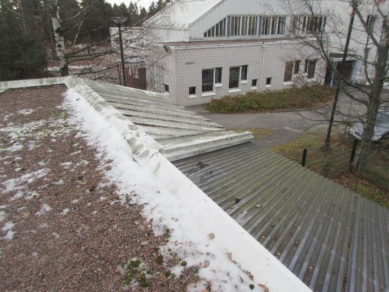 Kuvat 14 ja 15. Vesikaton suojakiveyksen päälle on kertynyt lehtiroskaa ja sammalta. Räystäspeltien maalipinta on kulunut. Kattokaivo on lähes tukossa.